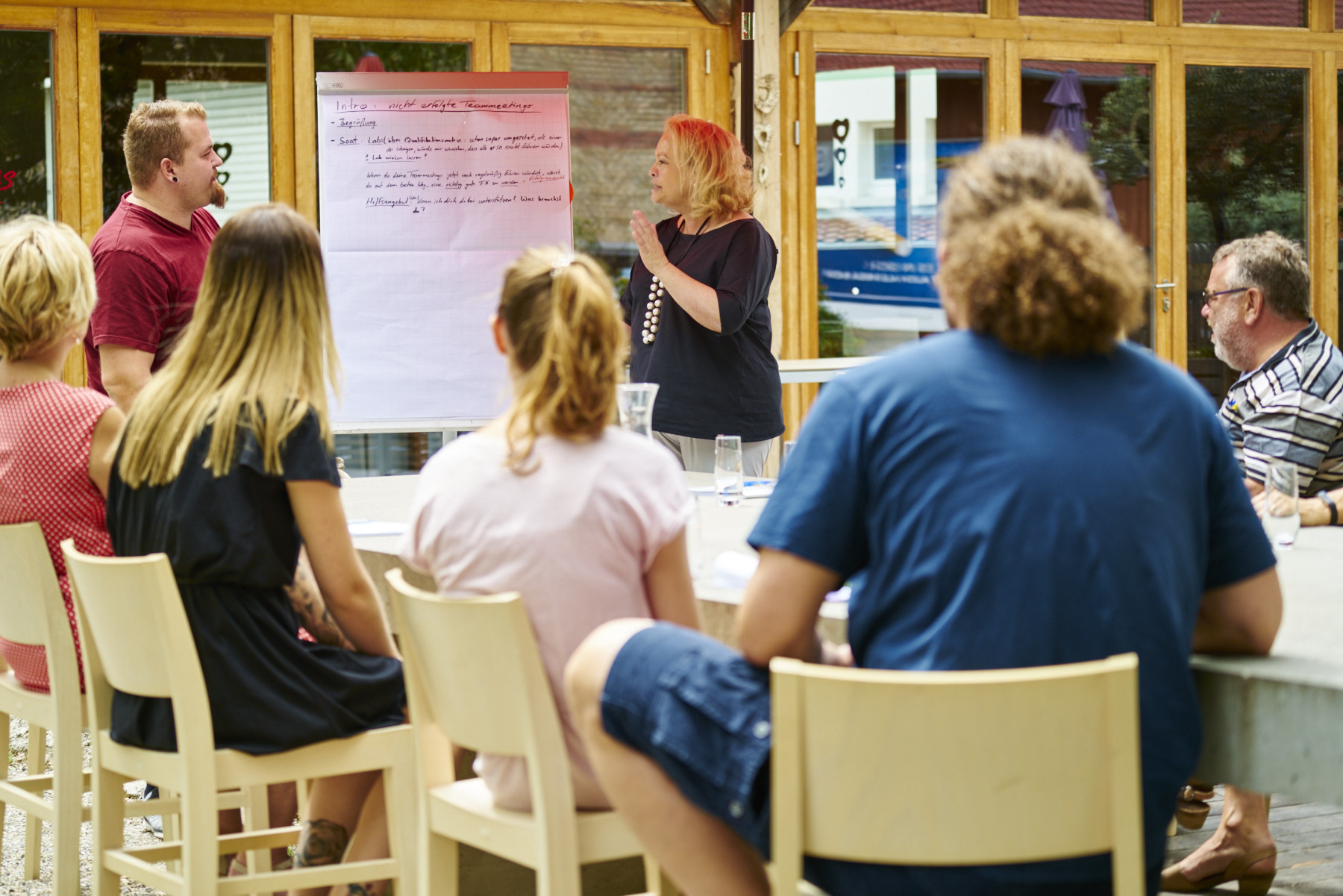 Seminarteilnehmende sitzen um einen Betontisch vor Flippchart